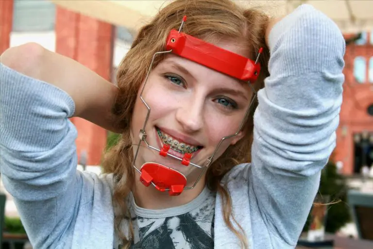 Confident young person with braces and headgear smiles outdoors, posing playfully; BeSpoke Orthodontics in Burtonsville, MD.