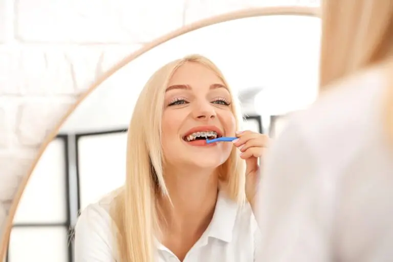 young woman metal braces toothbrush home - How To Floss With Braces in Burtonsville, MD