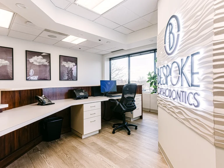 A sleek office in Burtonsville MD, features a desk, computer, decor, and BeSpoke Orthodontics’ illuminated sign.