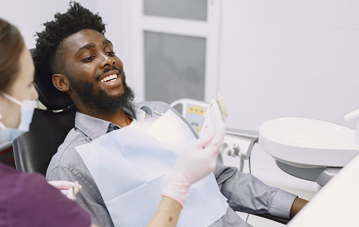At BeSpoke Orthodontics in Burtonsville, MD, a smiling man sits in a dental chair as the dentist shows him braces on a model.