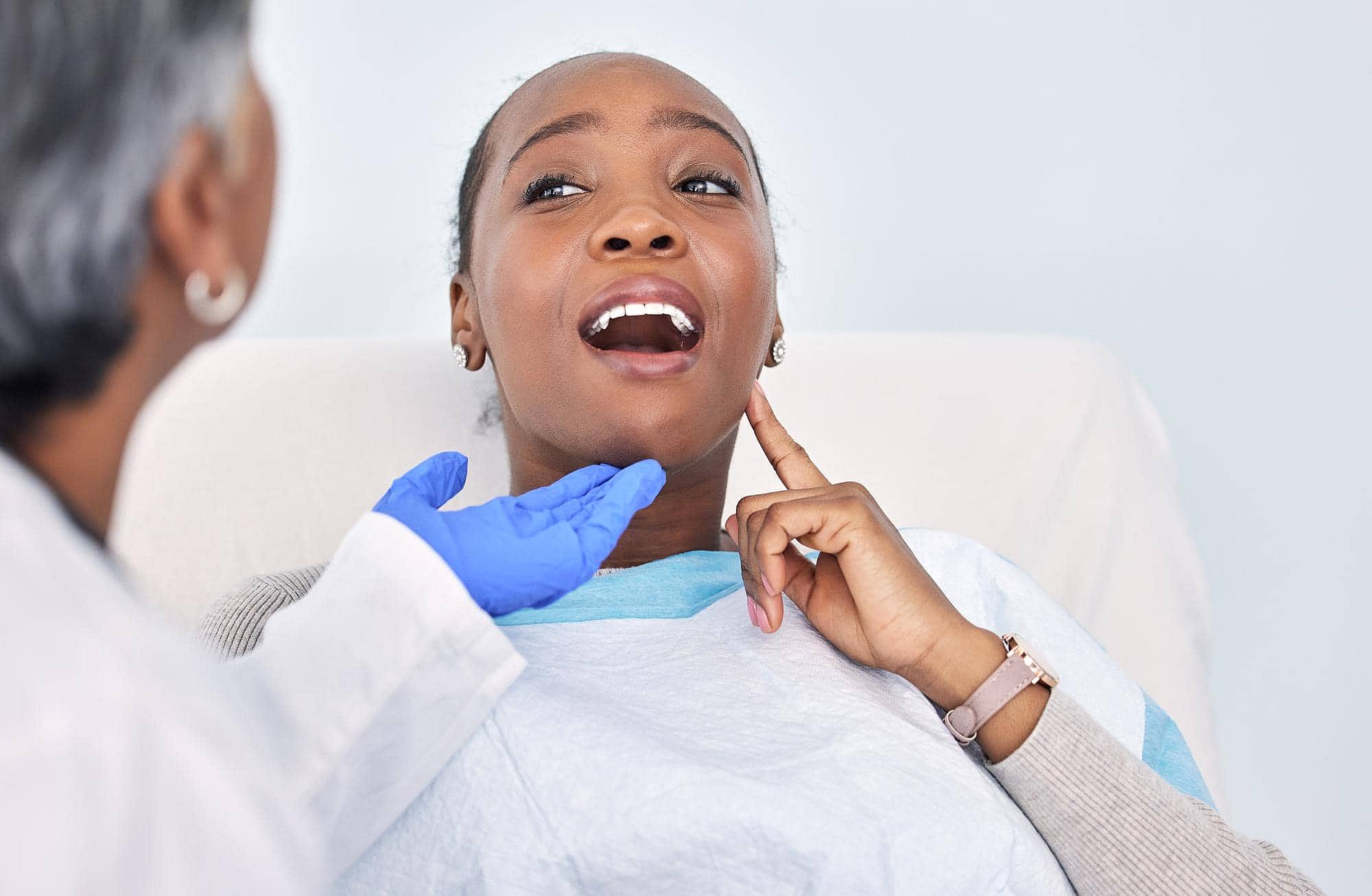 During a consultation at BeSpoke Orthodontics in Burtonsville, MD, a patient with braces points to her throat as her neck is examined.