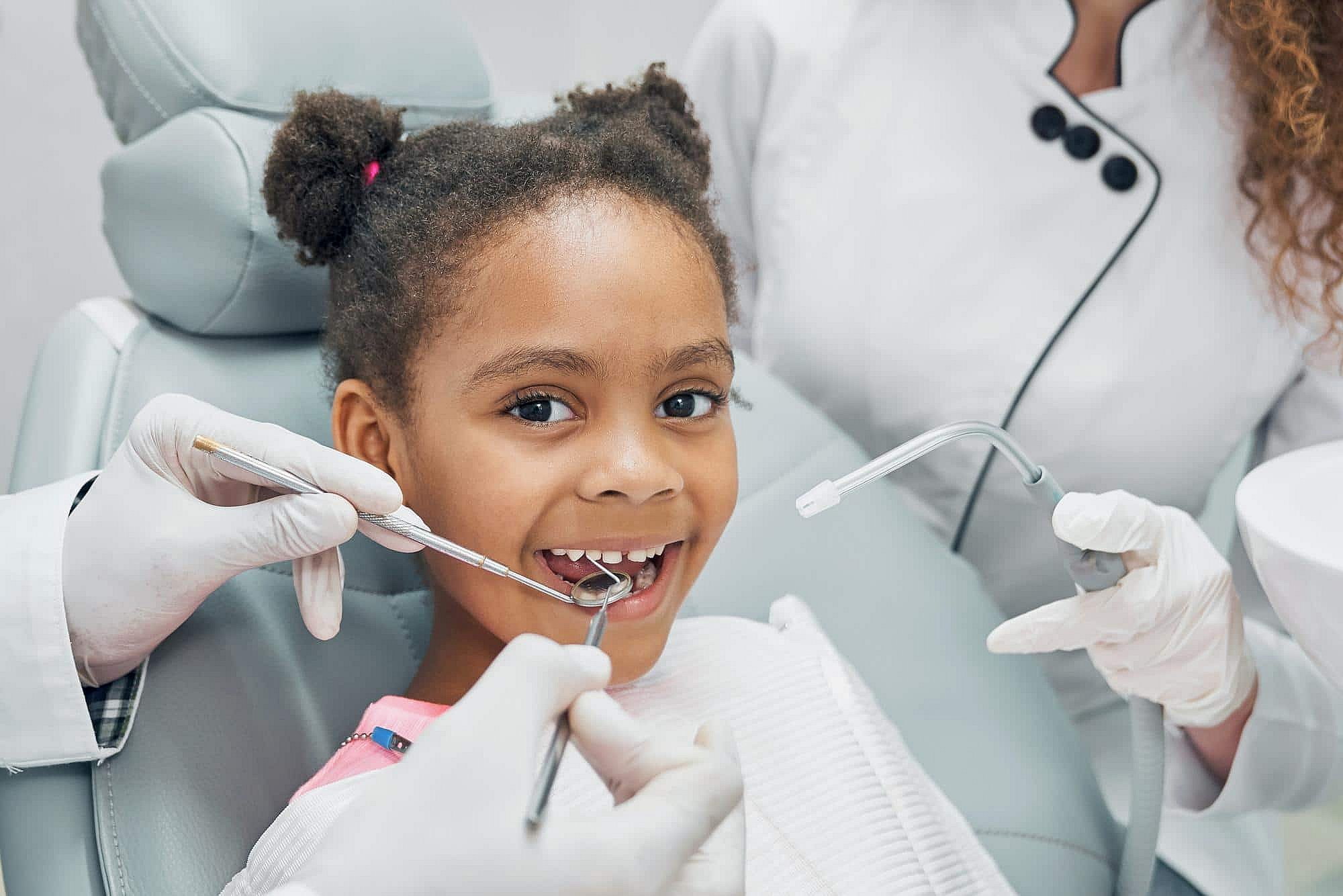 At BeSpoke Orthodontics in Burtonsville, MD, two dentists examine a young girl's teeth as she sits in a dental chair.