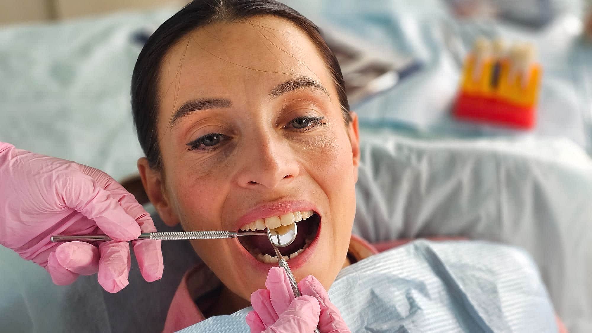 A dentist in pink gloves examines braces at BeSpoke Orthodontics in Burtonsville, MD as the patient sits in a dental chair.