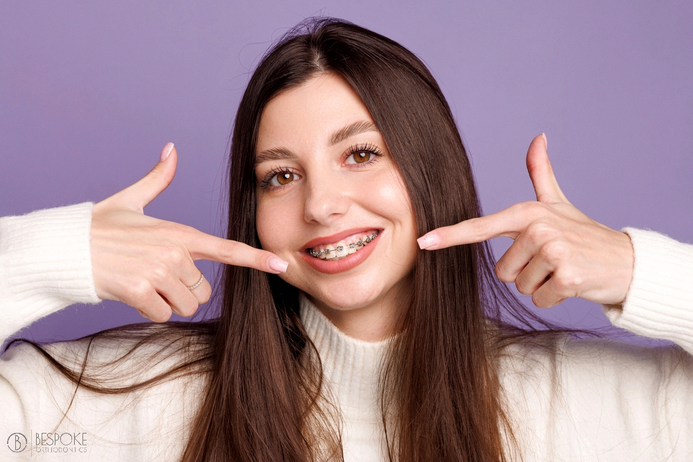 portrait girl braces woman happy metal braces shows sign - Braces for Overbite in Burtonsville, MD