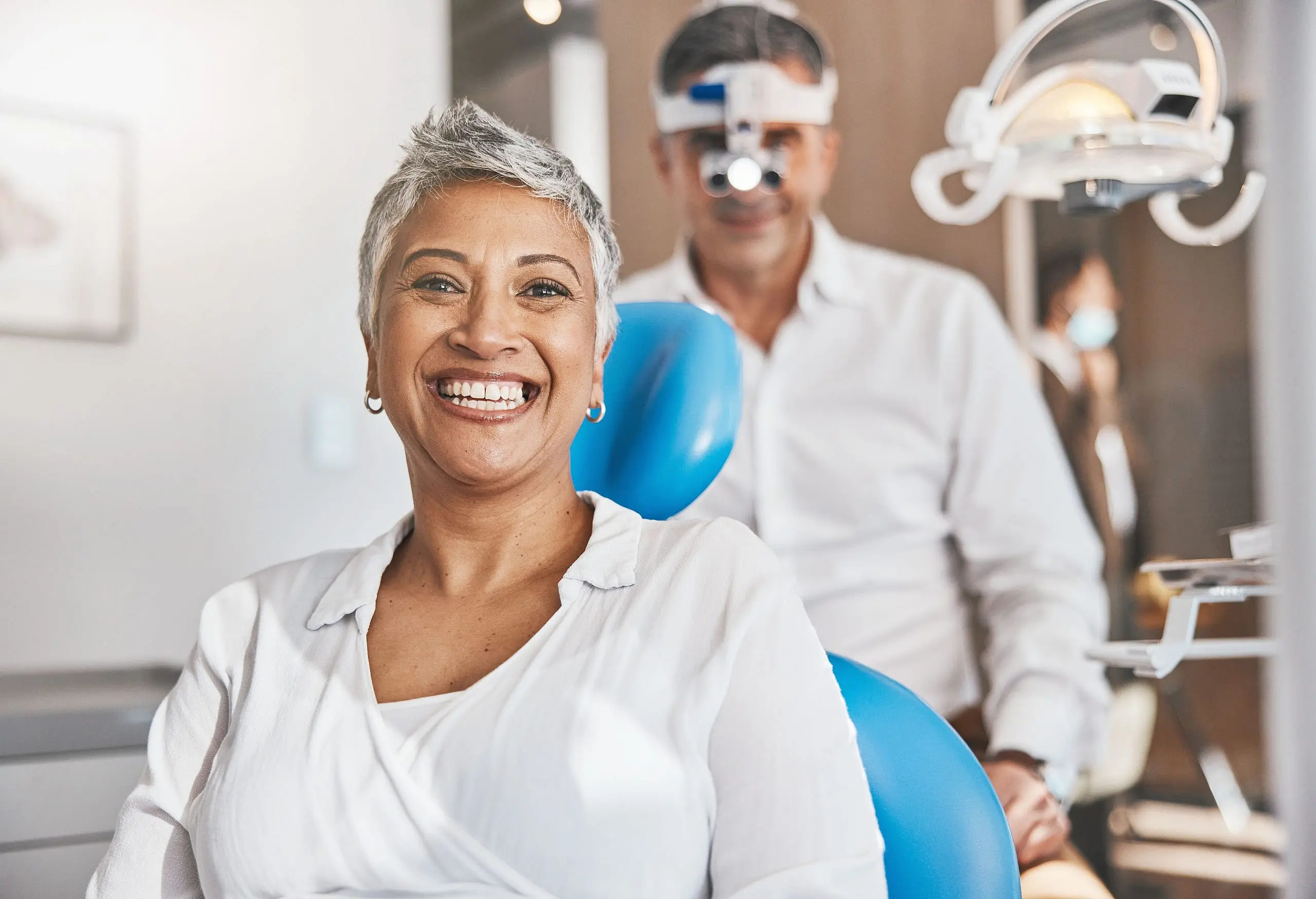 At BeSpoke Orthodontics in Burtonsville, MD, a smiling woman sits in a dental chair and adult orthodontics stands behind her.