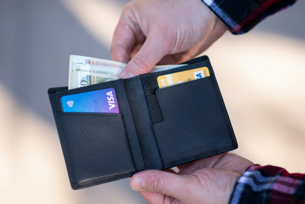 A person holds an open black wallet with cash and two Visa cards—showing BeSpoke Orthodontics in Burtonsville, MD offers flexible Invisalign Payment Plans.