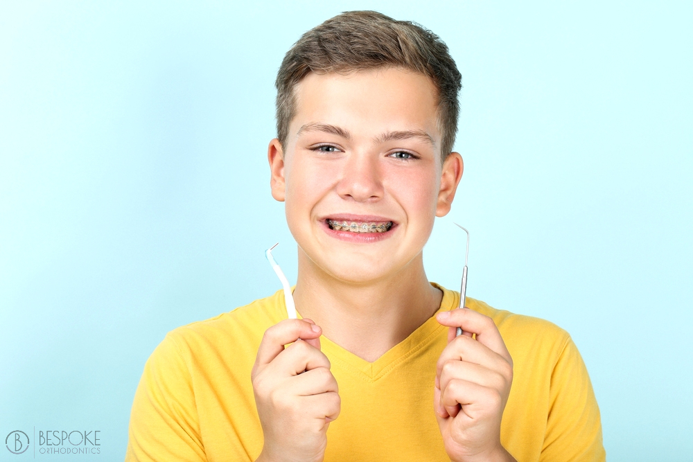 young man with metal braces toothbrush dentist tool - How To Floss With Braces in Burtonsville, MD 